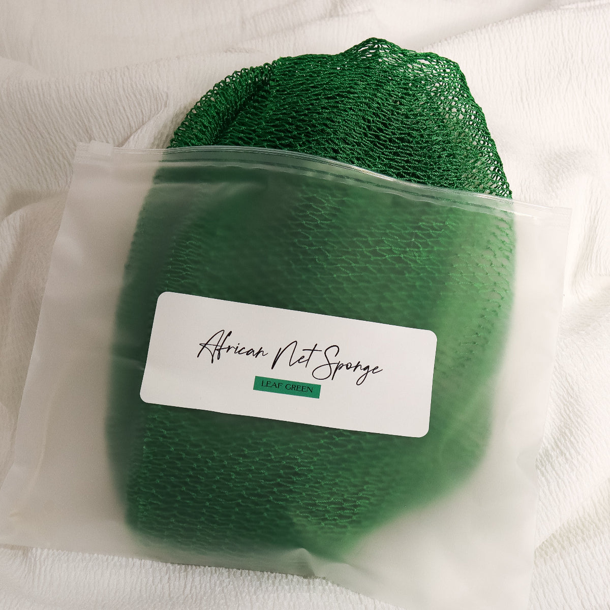 Leaf green African net sponge in a clear zip bag with a product label on a white background