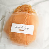 Light brown African net sponge in a clear zip bag with a product label on a white background