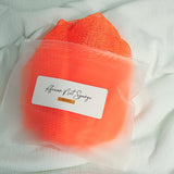 Orange African net sponge in a clear zip bag with a product label on a white background