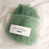 Seafoam-colored African net sponge in a clear zip bag with a product label on a white background