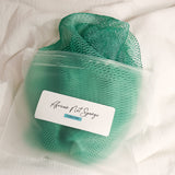 Turquoise African net sponge in a clear zip bag with a product label on a white background