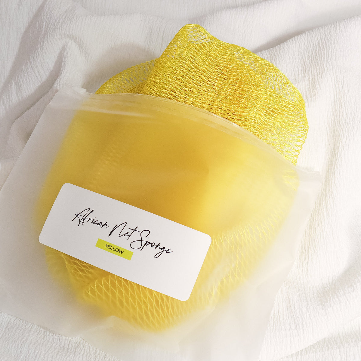 Yellow African net sponge in a clear zip bag with a product label on a white background