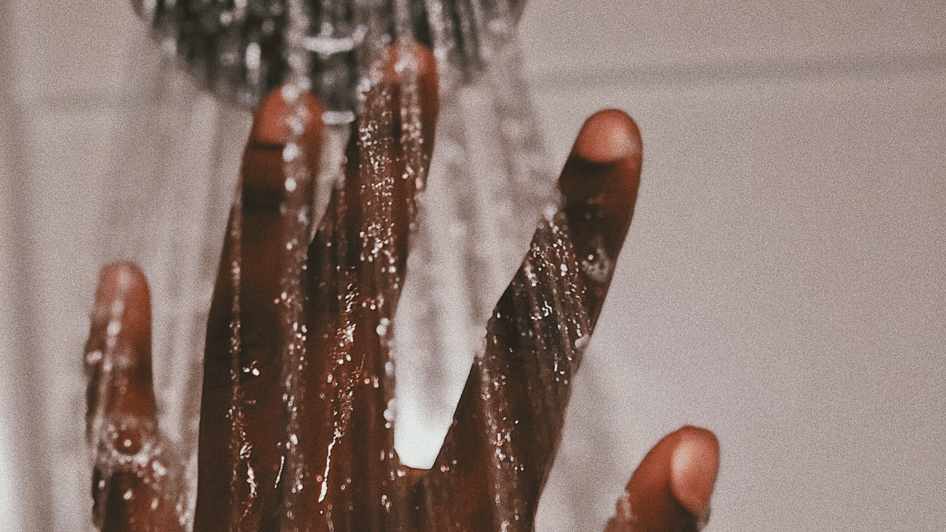 Person holding their hand up to a running shower head.