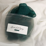 Emerald green African net sponge in a clear zip bag with a product label on a white background